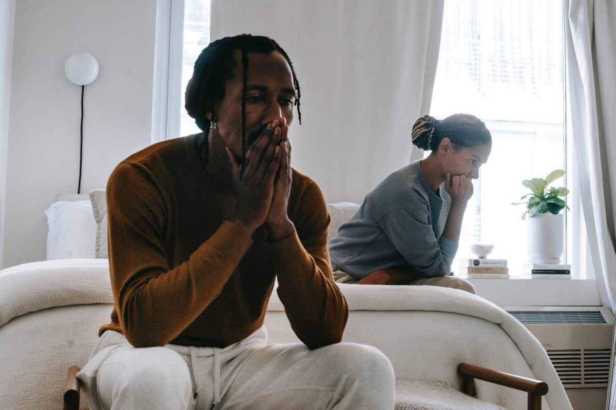 unhappy black couple sitting on bed after having argument